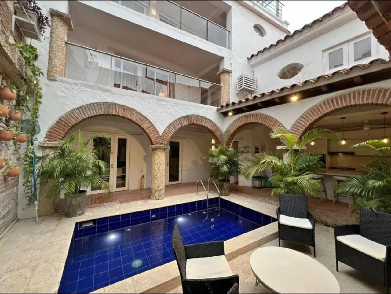 Casa en el Centro Histórico de Cartagena — Patio central con piscina, arcos de ladrillo y palmeras de la casa en el Centro Histórico de Cartagena